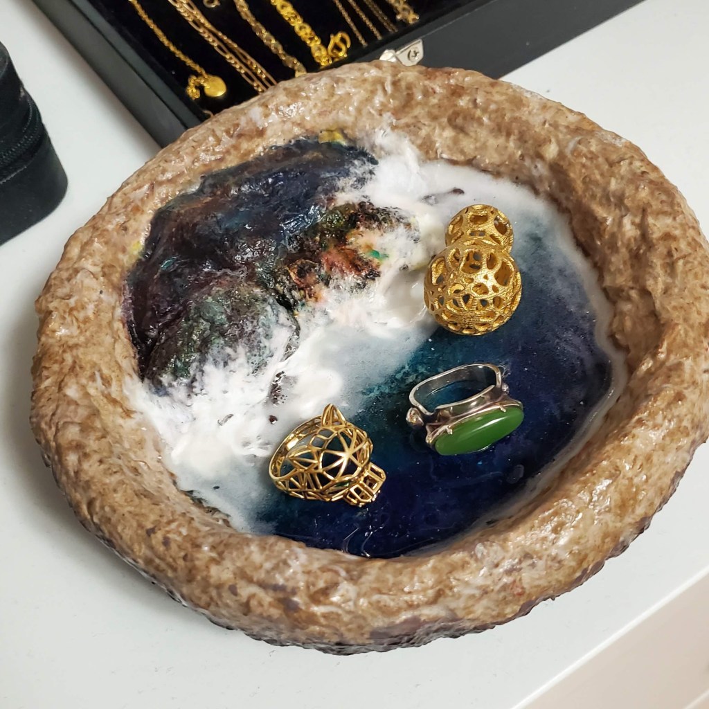 A handmade jewellery dish resembles a coastline with waves crashing on some rocks. 